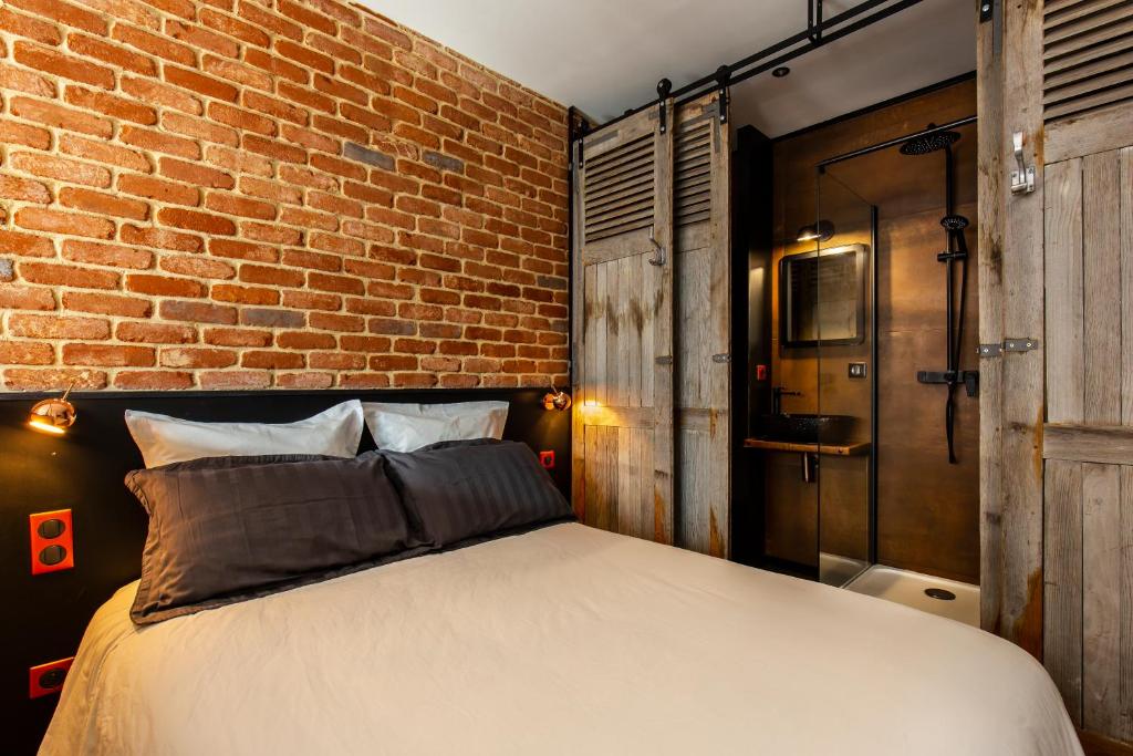 ルーアンにあるSuite Vintage Rouenのレンガの壁とベッドが備わるベッドルーム1室が備わります。