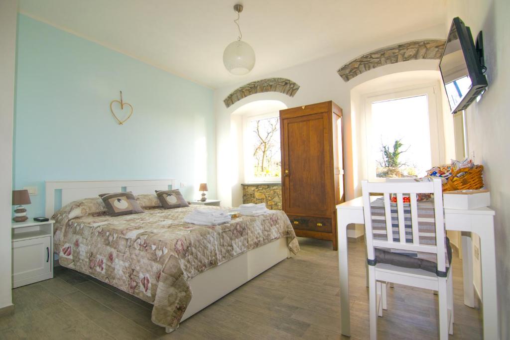 1 dormitorio con 1 cama, TV y silla en I TRE GRAPPOLI, en Corniglia