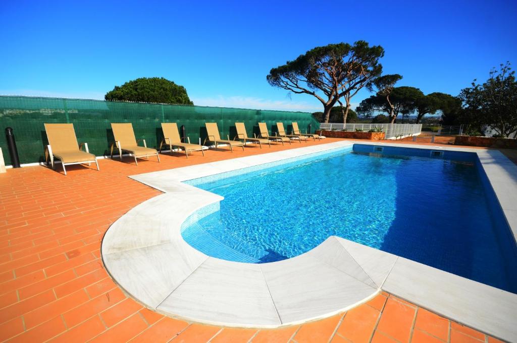 a swimming pool with lounge chairs on a brick patio at Villa Carlivo in Albufeira