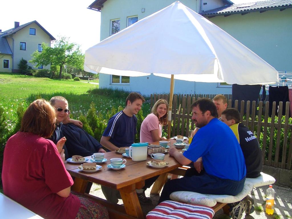a group of people sitting at a picnic table under an umbrella at Bauernhof Familie Tauber-Scheidl in Grossmeinharts