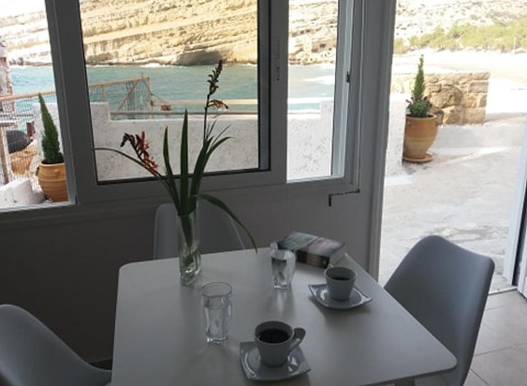 a white table with a vase of flowers on it at Studio Rafaela in Matala