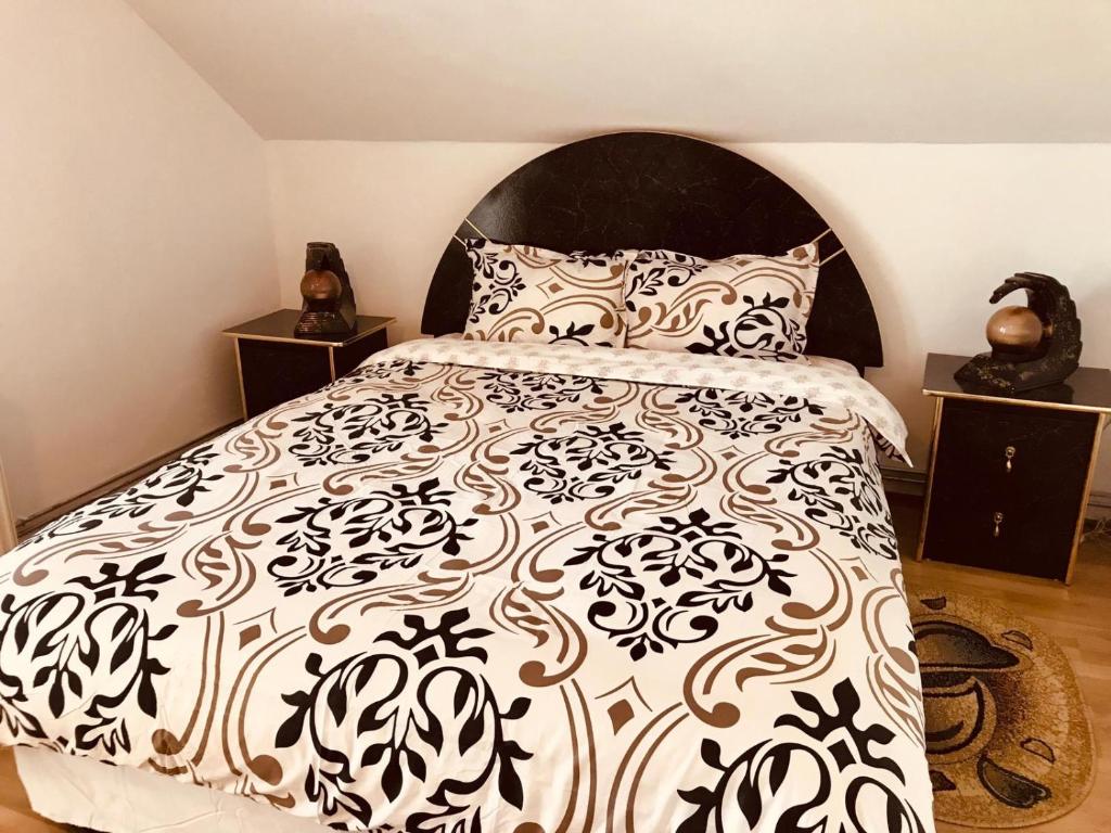 a bedroom with a bed with a black and white comforter at Vila Ekooos in Braşov