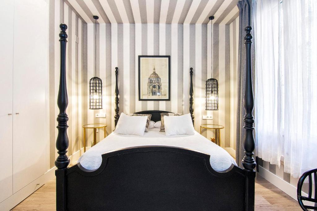 グラナダにあるCentral Deluxe Apartments by Apolo Homesの縞模様の壁の客室で、黒いベッド1台が備わります。
