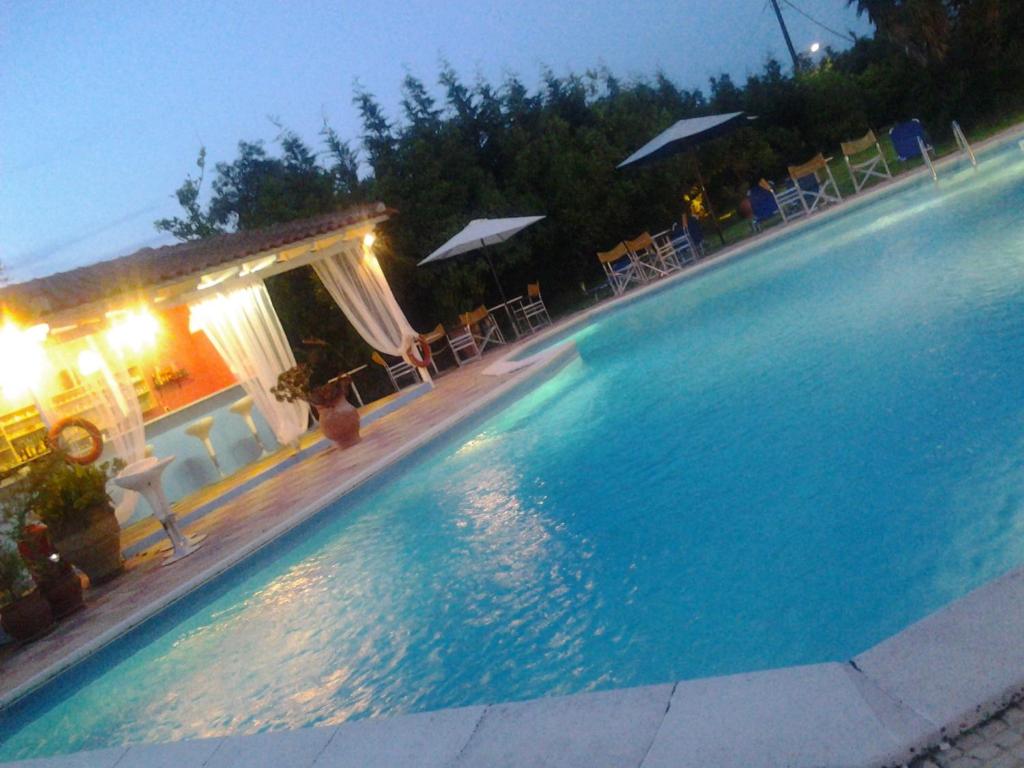 una gran piscina por la noche con sillas y sombrillas en Villa Pap, en Preveza