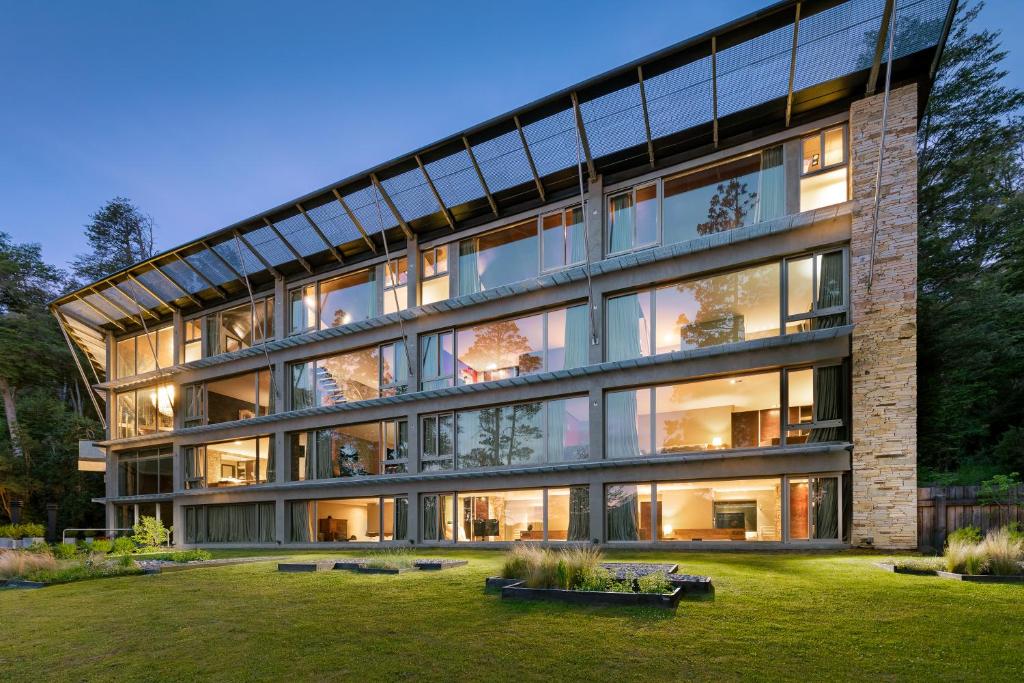 a large glass building with a yard in front of it at Calfuco Wine Hotel & Spa in Villa La Angostura