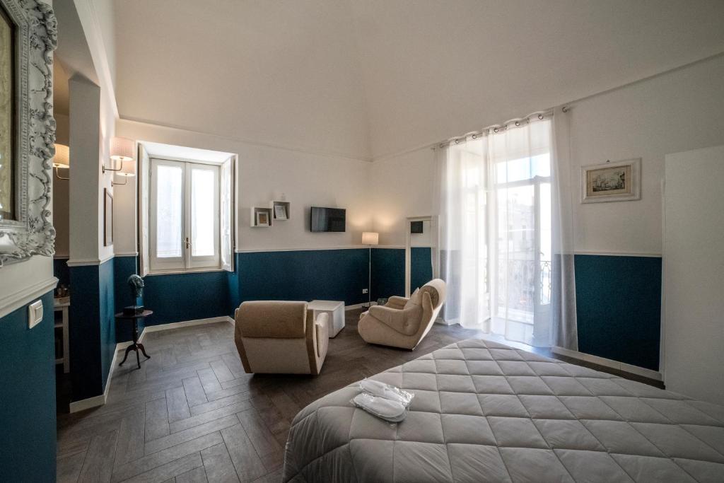a bedroom with a bed and two chairs and a window at Novecento Dimore di Poesia in Trani