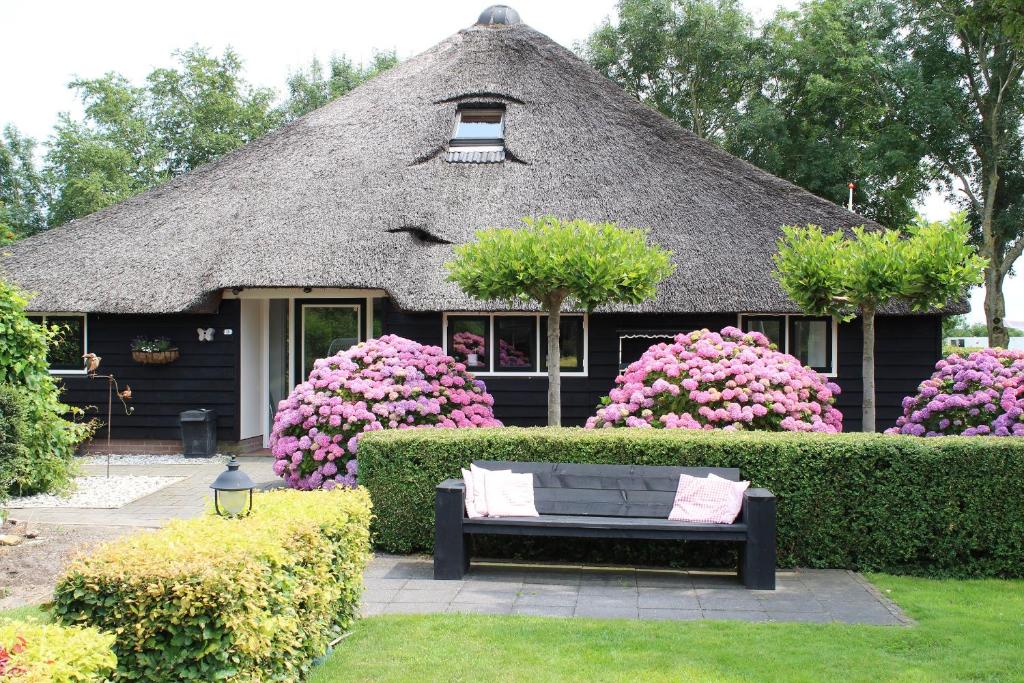 una casa con tetto di paglia, panchina e fiori di B&B Heida a Giethoorn
