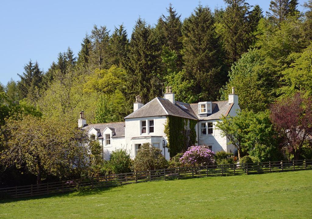 una casa blanca en un campo con árboles en Craigadam en Kirkpatrick Durham