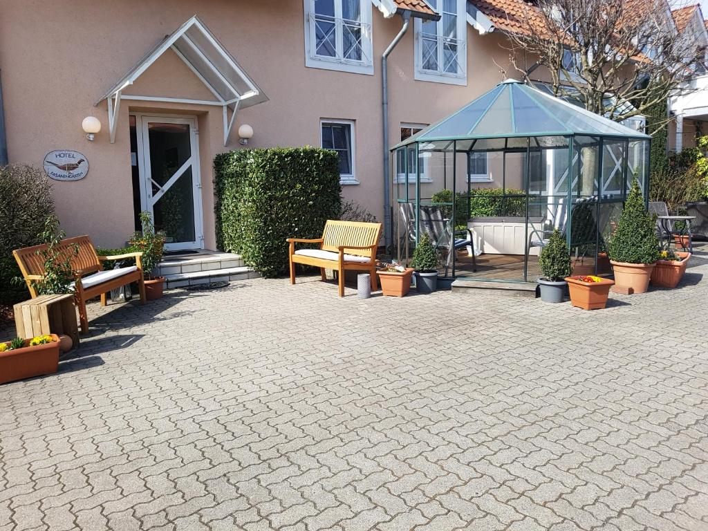 eine Terrasse mit Bänken und einem Pavillon vor einem Haus in der Unterkunft Hotel Fasanengarten in Sarstedt