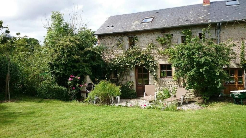 une ancienne maison en pierre avec une cour verdoyante dans l'établissement La Petite Maison, à Bricqueville