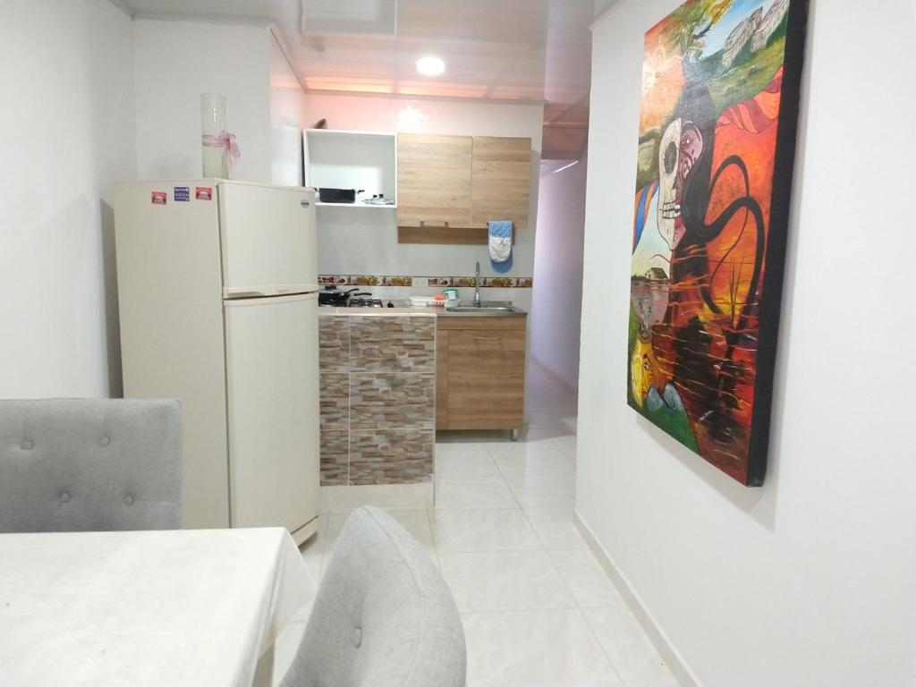 Il comprend une cuisine équipée d'un réfrigérateur blanc et d'une peinture murale. dans l'établissement Apartamentos Maiver, à Ríohacha
