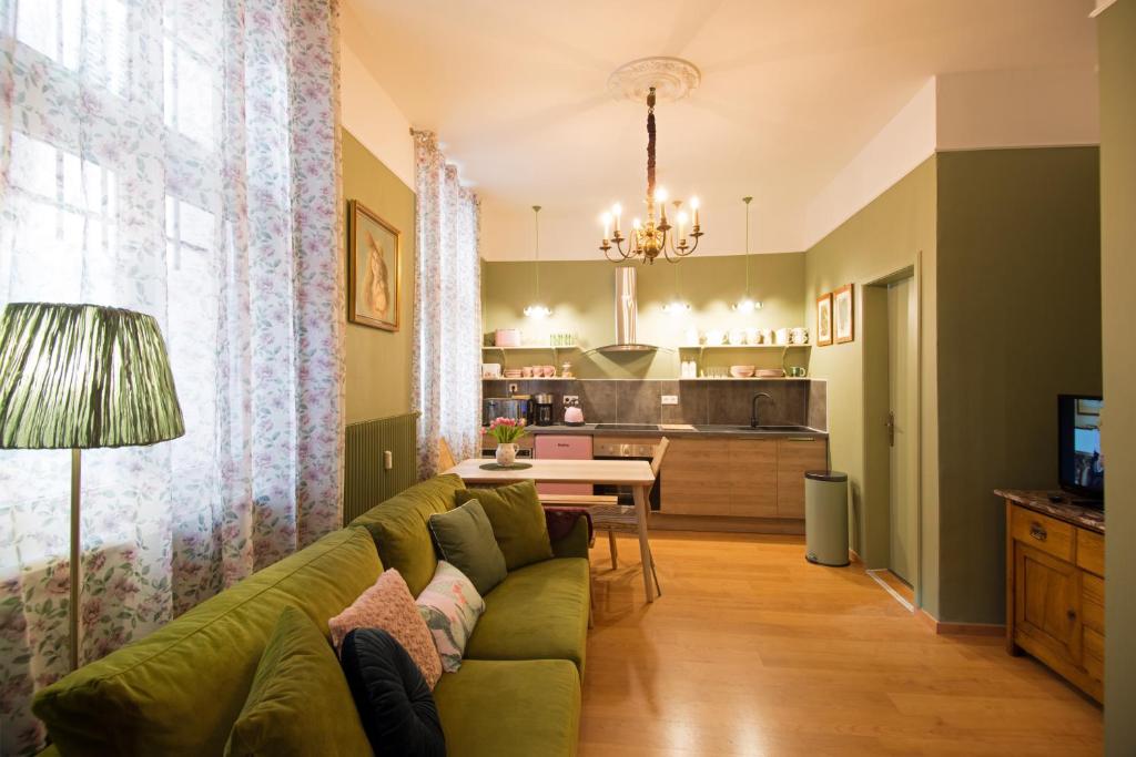 a living room with a green couch and a kitchen at " Mademoiselle " 17 Boulevard du Champ de Mars in Colmar