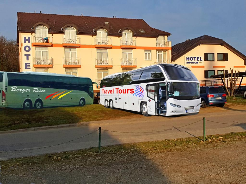 zwei Busse, die auf einem Parkplatz vor einem Gebäude geparkt sind in der Unterkunft Hotel Imperium in Moravske-Toplice