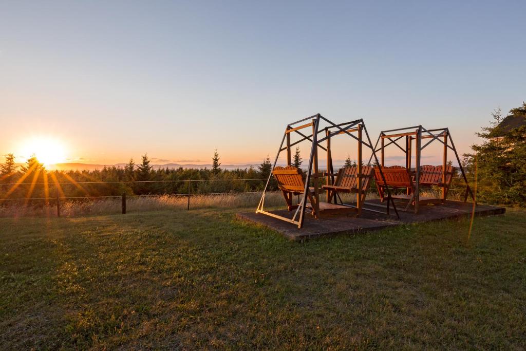 a swing set in a field with the sunset in the background at Le Fraser Motel in Rivière-du-Loup