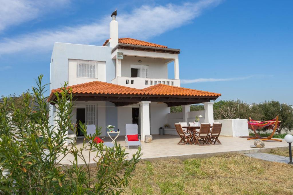 een wit huis met een veranda en een tafel en stoelen bij Alkion Villa in Gennadi