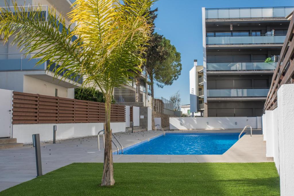a palm tree in front of a building with a swimming pool at Hauzify I Apartaments Coral in Torredembarra