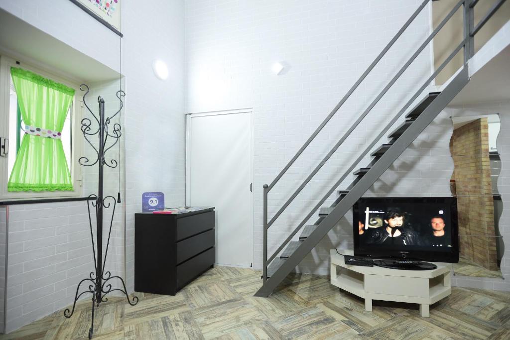 - un salon avec une télévision et un escalier dans l'établissement Santa Chiara Apartment, à Naples