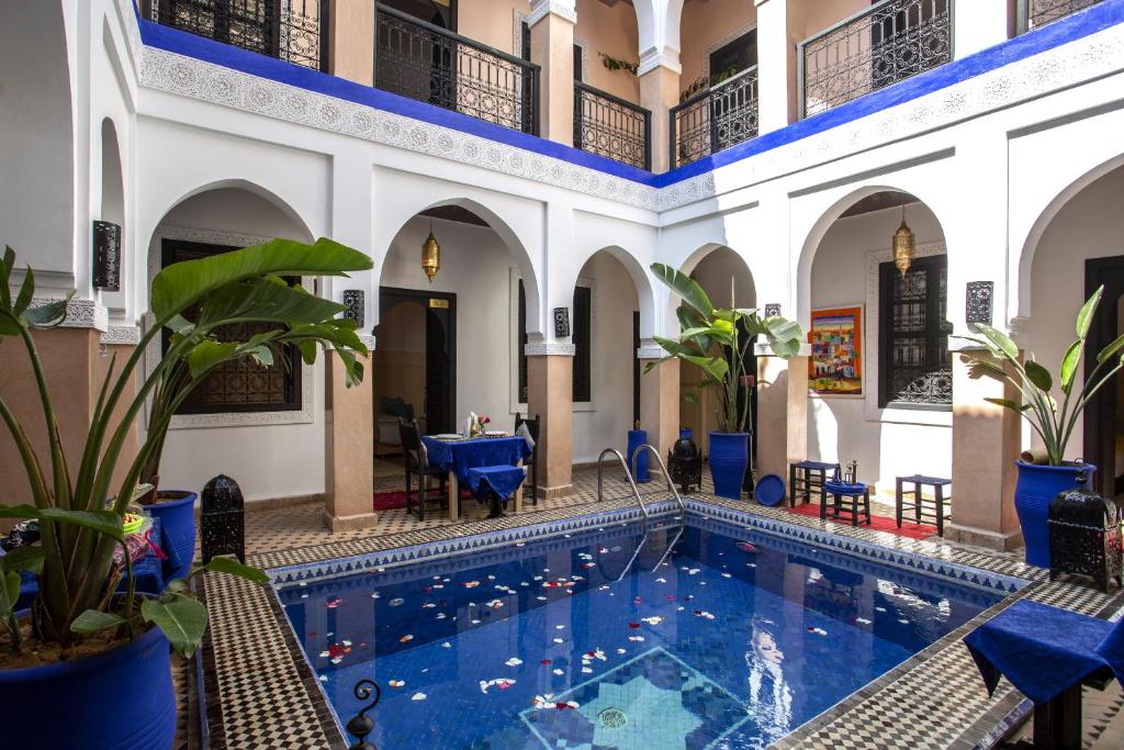 a pool in a building with blue chairs and tables at Riad Ciel d'Orient in Marrakesh