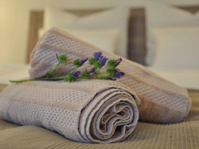une serviette avec des fleurs assise sur un lit dans l'établissement Apartment Mida, à Fribourg-en-Brisgau