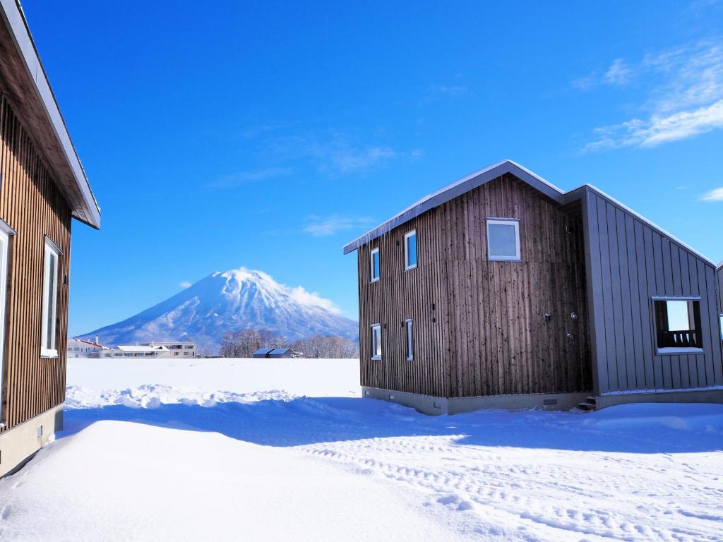 Niseko Highland Cottages في نيسيكو: حظيرة في الثلج مع جبل في الخلف