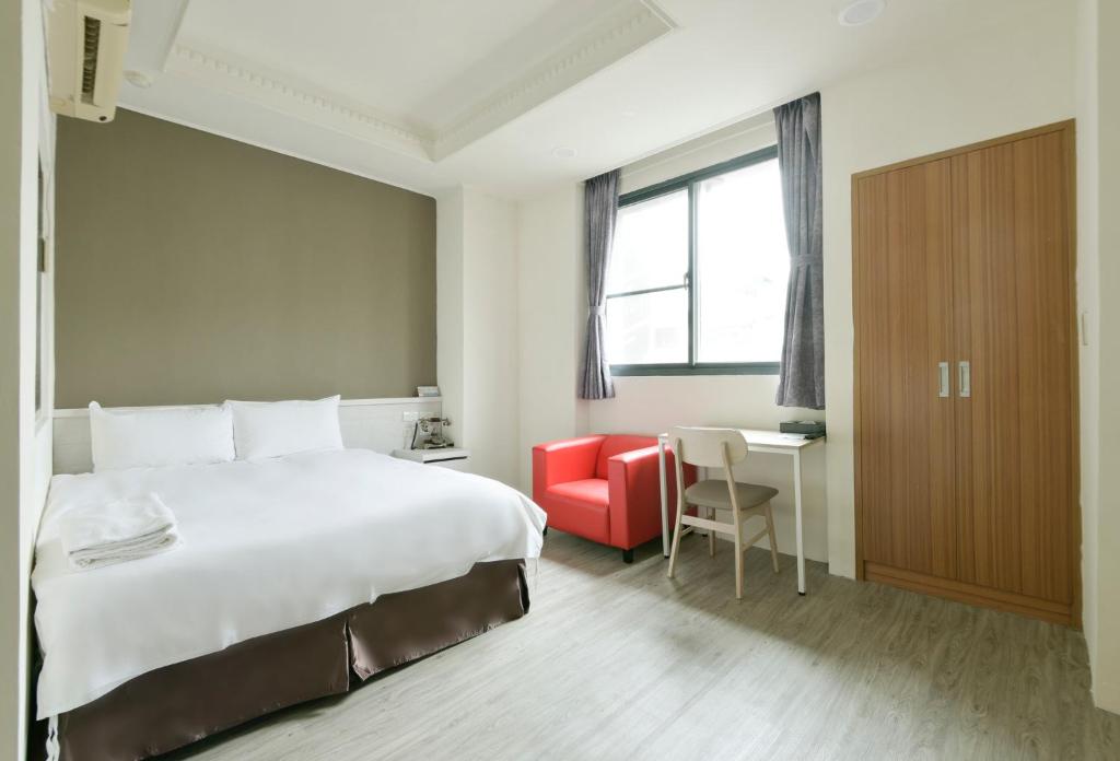 a hotel room with a large bed and a red chair at Raise Hotel Taichung in Taichung