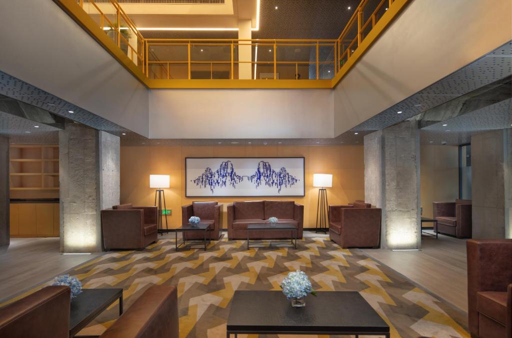 um lobby de um hotel com um sofá e mesas em Holiday Inn Express Beijing Shijingshan Parkview, an IHG Hotel em Pequim