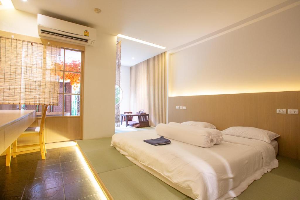 ein Schlafzimmer mit einem weißen Bett und einem Tisch in der Unterkunft Baan Kashiwaya in Bangkok