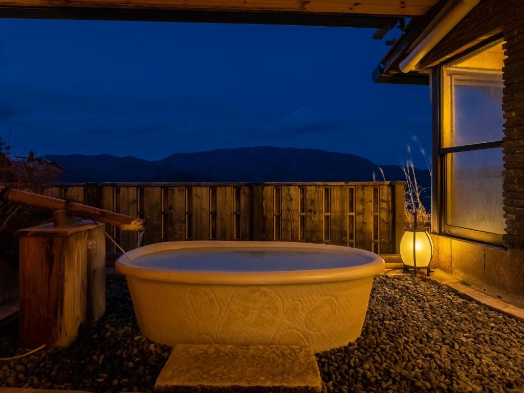 una grande vasca seduta fuori da una casa di notte di Shirayunoyado Yamadaya Hakone Gora a Hakone