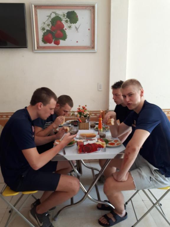 un grupo de hombres sentados en una mesa comiendo comida en Hotel Thanh Minh, en Châu Làng Chánh