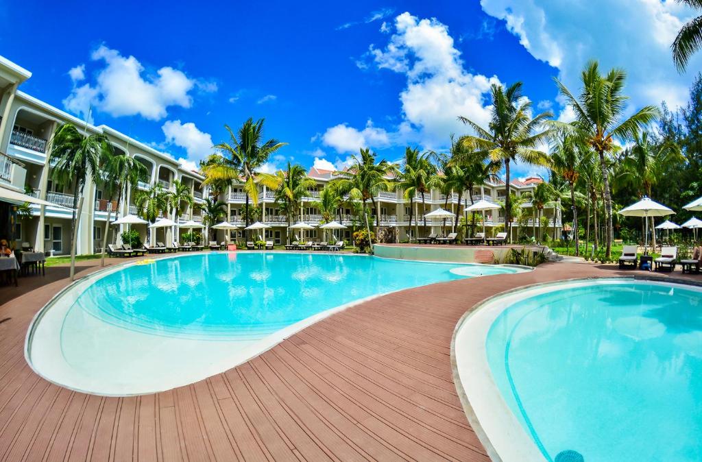 einen Pool in einem Resort mit Palmen und Sonnenschirmen in der Unterkunft Tarisa Resort & Spa in Mont Choisy
