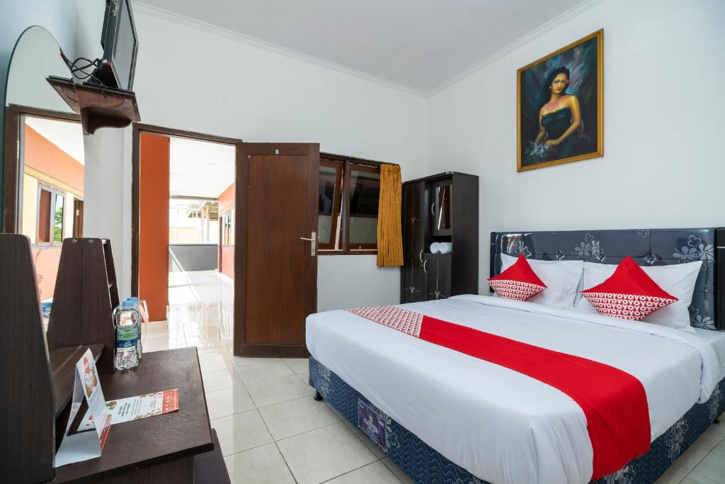 1 dormitorio con 1 cama grande con almohadas rojas y blancas en OYO 636 Apartmen Kak Okoh en Canggu