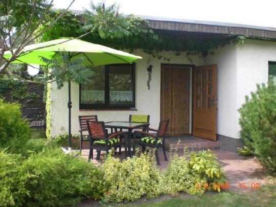 eine Terrasse mit einem Tisch, Stühlen und einem Sonnenschirm in der Unterkunft Ferienhaus am See in Jabel