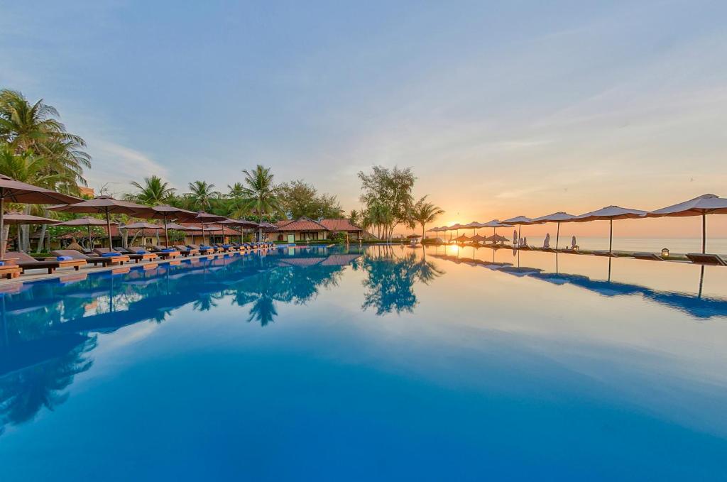 einen Pool mit Stühlen und Sonnenschirmen in einem Resort in der Unterkunft Seahorse Resort & Spa in Mui Ne