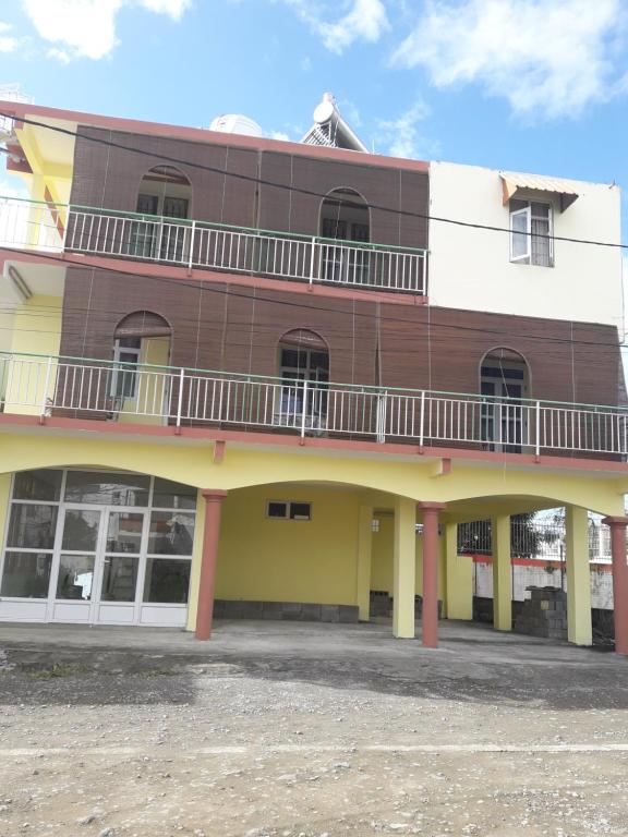 a brown and yellow building with a balcony at Bano Tourist Residence - 650 meters from Grand Bay Beach in Grand-Baie
