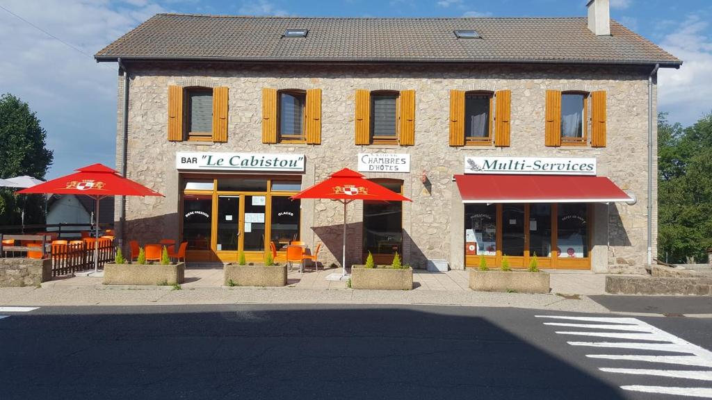 a building with tables and umbrellas in front of it at Le cabistou in Devesset