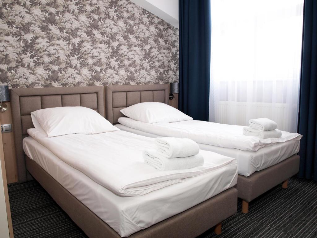 two beds in a room with white sheets and pillows at Hotel Duet in Człuchów