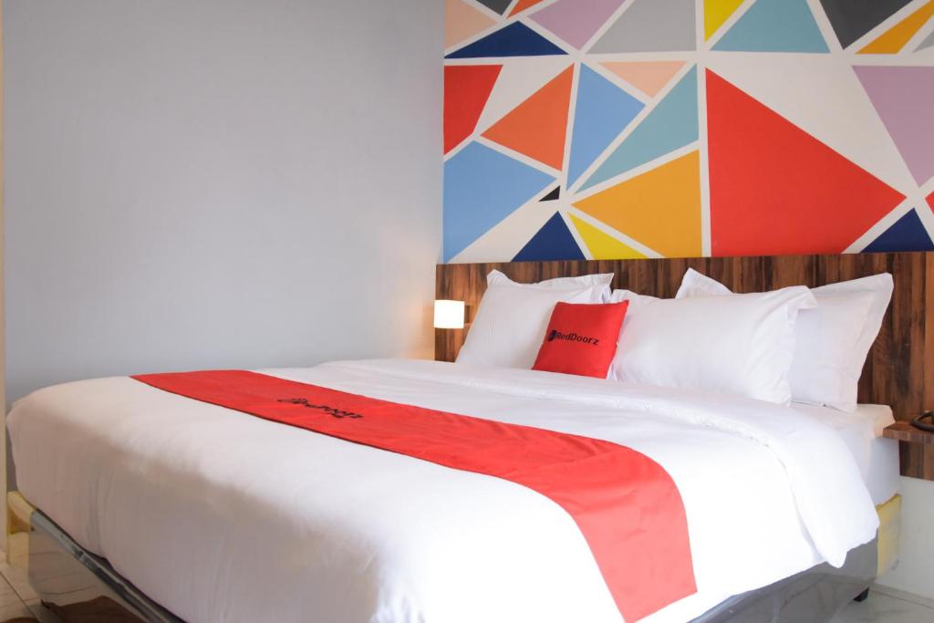 um quarto com uma cama branca e uma parede colorida em RedDoorz Plus near UNIMED Medan em Medan