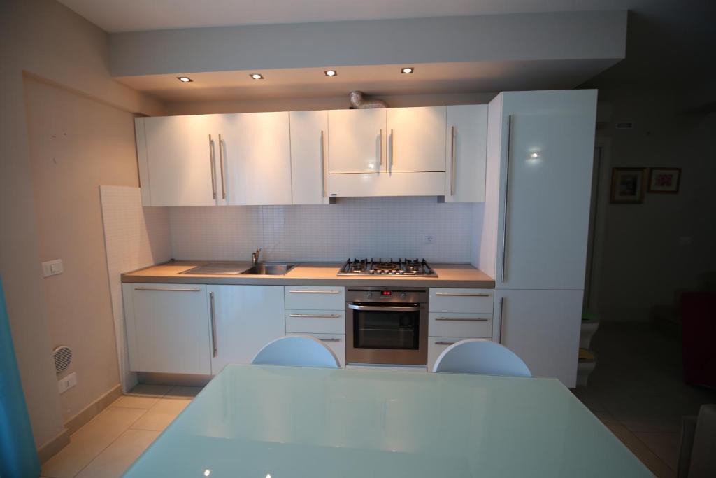 une cuisine avec des armoires blanches et un réfrigérateur blanc dans l'établissement Appartamenti Solemare, à San Benedetto del Tronto