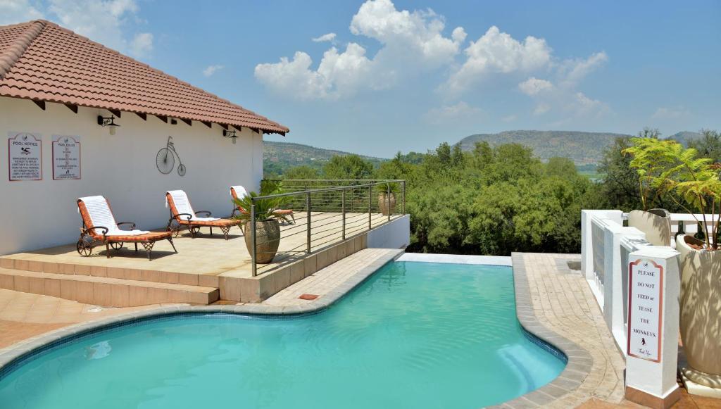 a swimming pool with a view of a house at Indlovukazi Guesthouse in Hartbeespoort