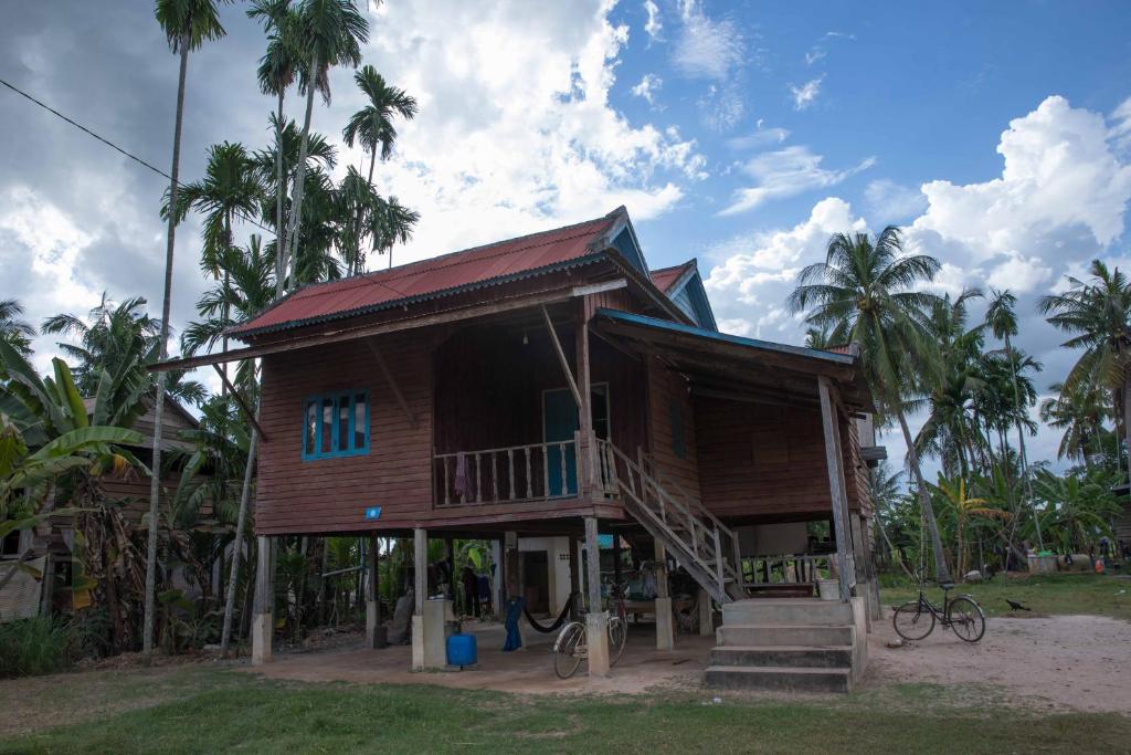 una pequeña casa de madera con escaleras y palmeras en Chansor Community Homestay 18 en Phumĭ Trach Pôk (2)