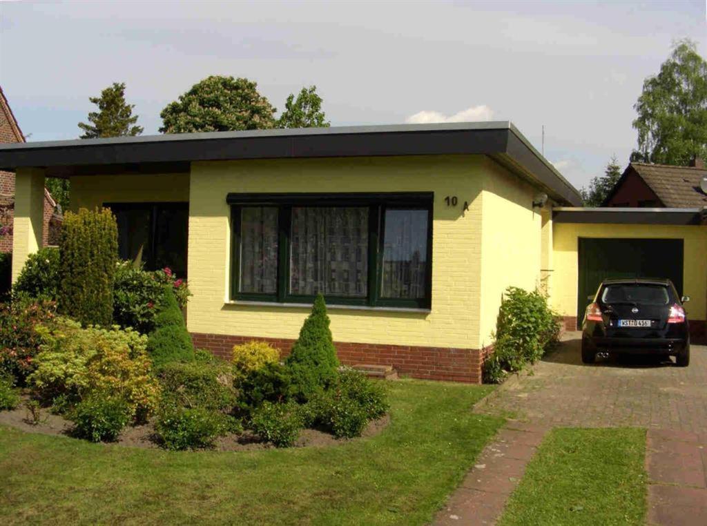 ein gelbes Haus mit einem davor geparkt in der Unterkunft Ferienhaus Alte Straße in Bad Zwischenahn