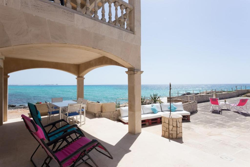 un patio con sedie, tavolo e vista sull'oceano di Maison Ses Covetes a Ses Covetes