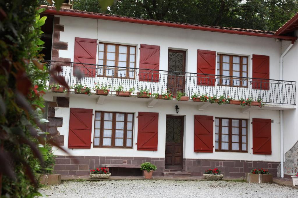 a white house with red shutters and a balcony at Gîte altzia haut in Saint-Michel