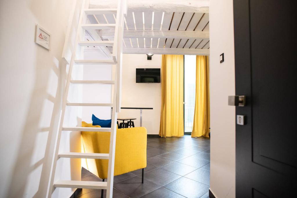 eine Leiter, die zu einem Wohnzimmer mit einem gelben Stuhl führt in der Unterkunft InCentro B&B in Milazzo