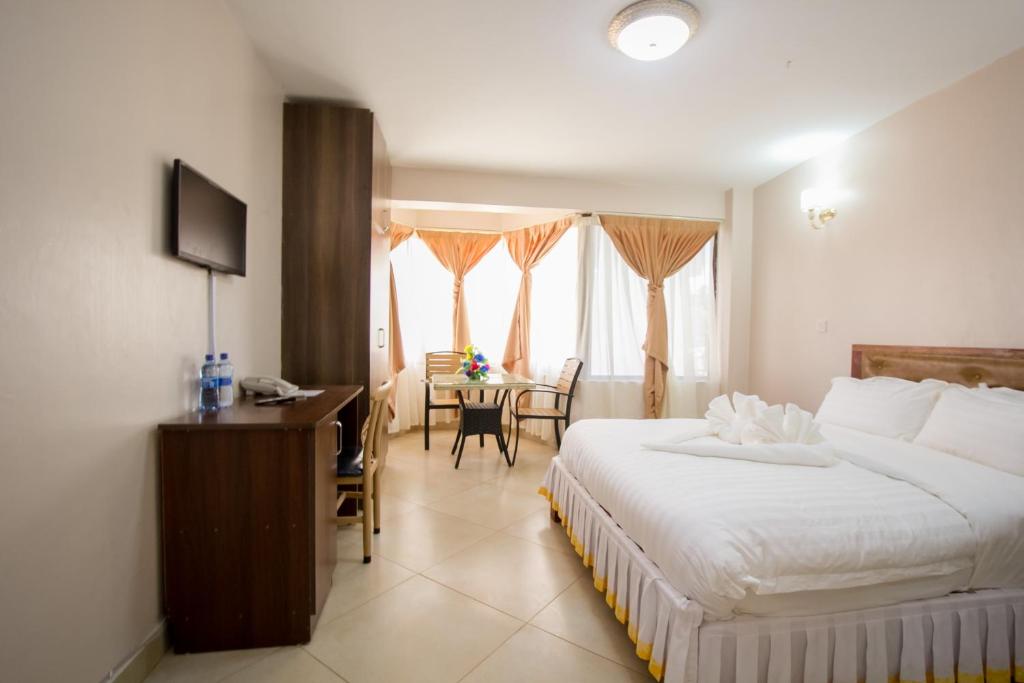 una camera con letto, scrivania e tavolo di Paleo Hotel and Spa a Thika