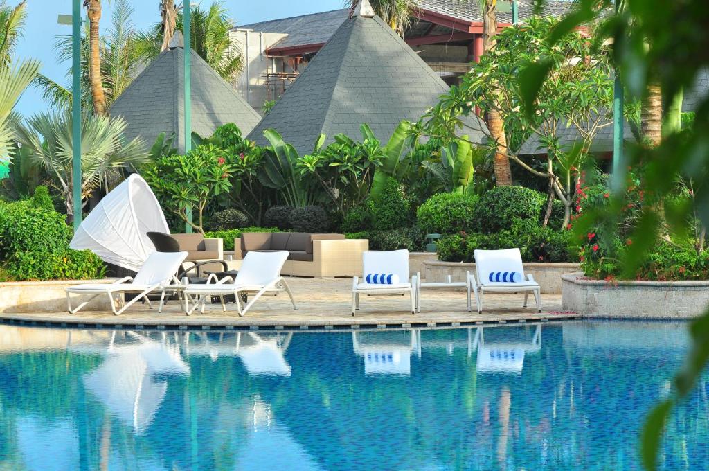 a group of lounge chairs and a swimming pool at Grand Hotel Haikou - Managed by Accor in Haikou
