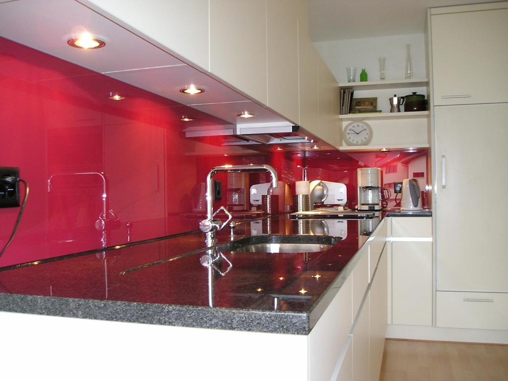 uma cozinha com um lavatório e paredes vermelhas em Ferienwohnung Schaap-Müller em Andermatt