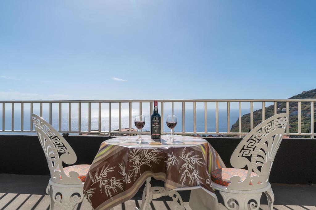 una mesa con 2 copas de vino en el balcón en Apartamento Teixeira, en Arco da Calheta