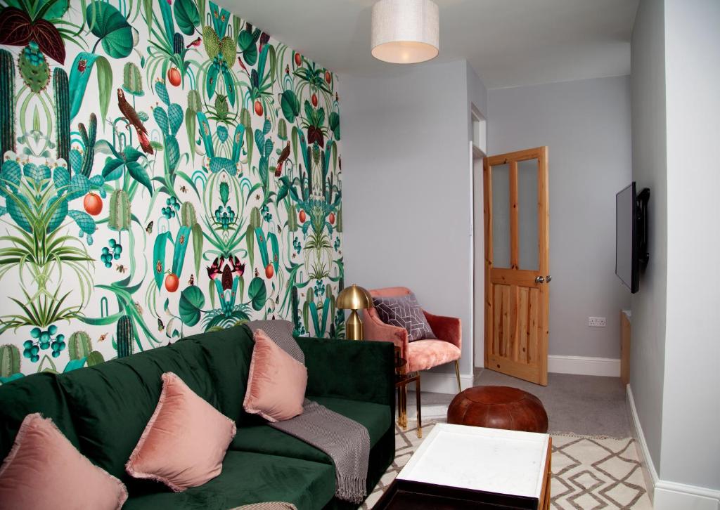 a living room with a green couch and a floral wallpaper at The Old Post Office - Bright & Modern 4BDR Townhouse in Oxford