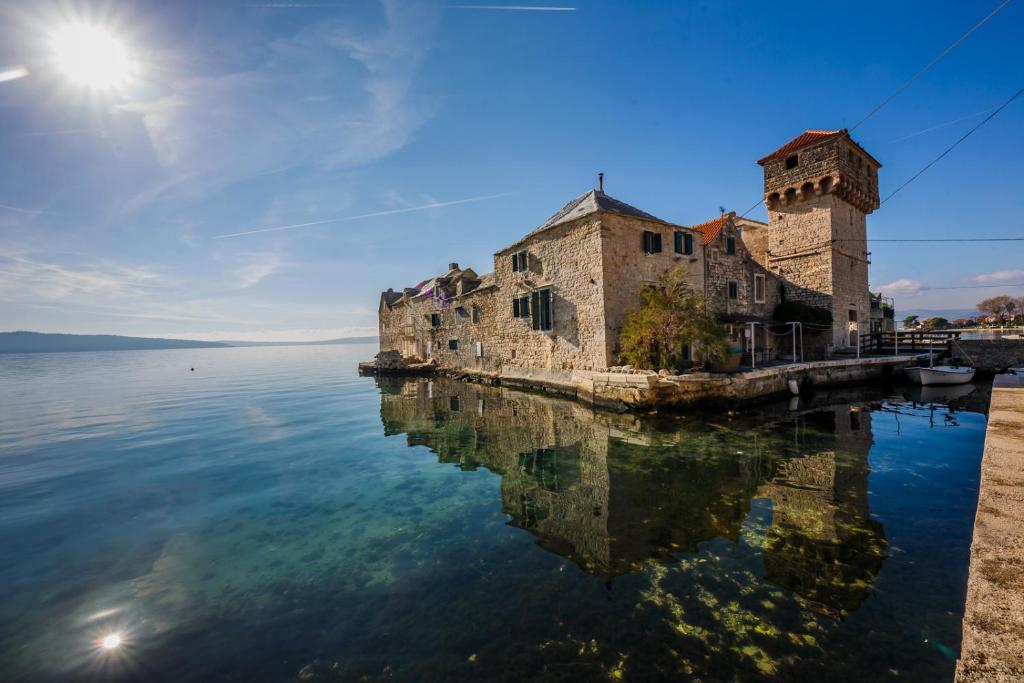 un antiguo edificio sobre el agua con su reflejo en Water Castle House en Kaštela